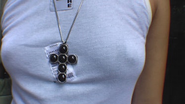 Close-up of a person wearing a white tank and a black cross