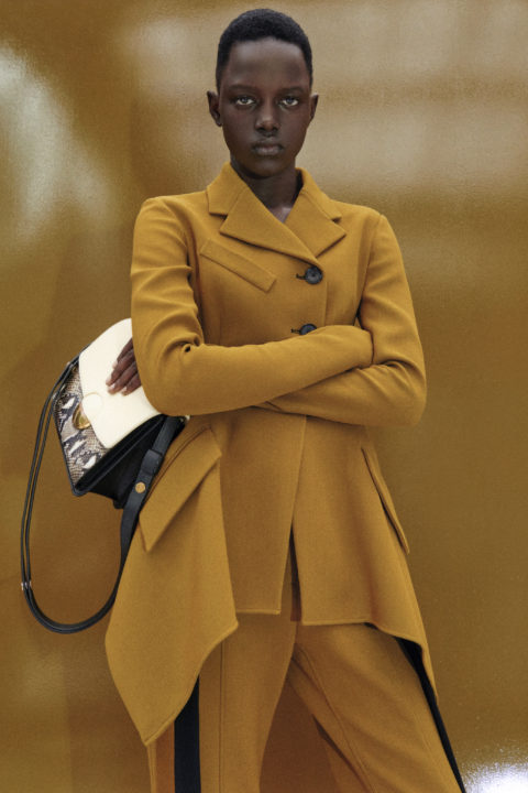 The model wears a mustard jacket and carries a Proenza Schouler bag, released spring 2023