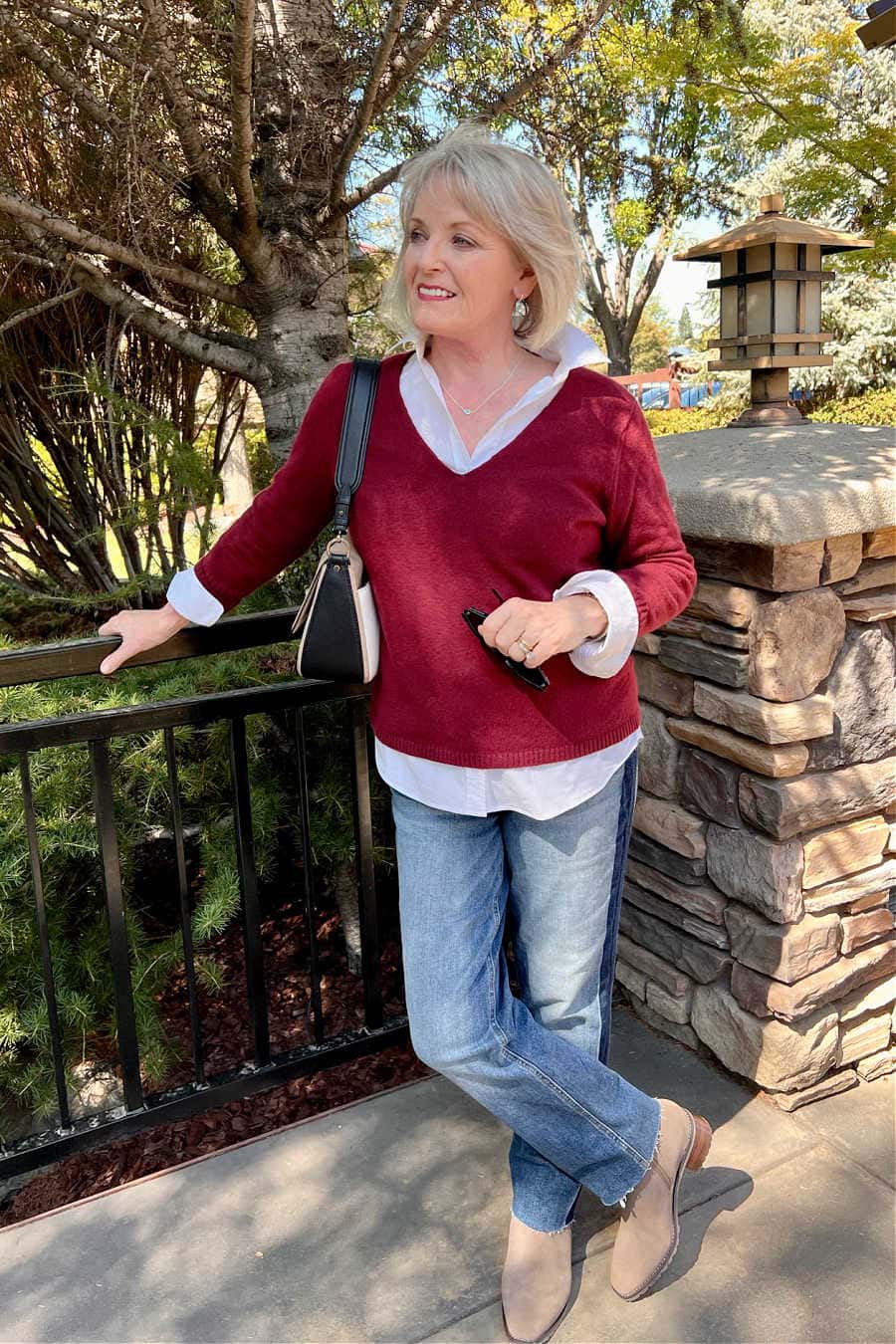 Woman wearing burgundy sweater over white shirt and jeans