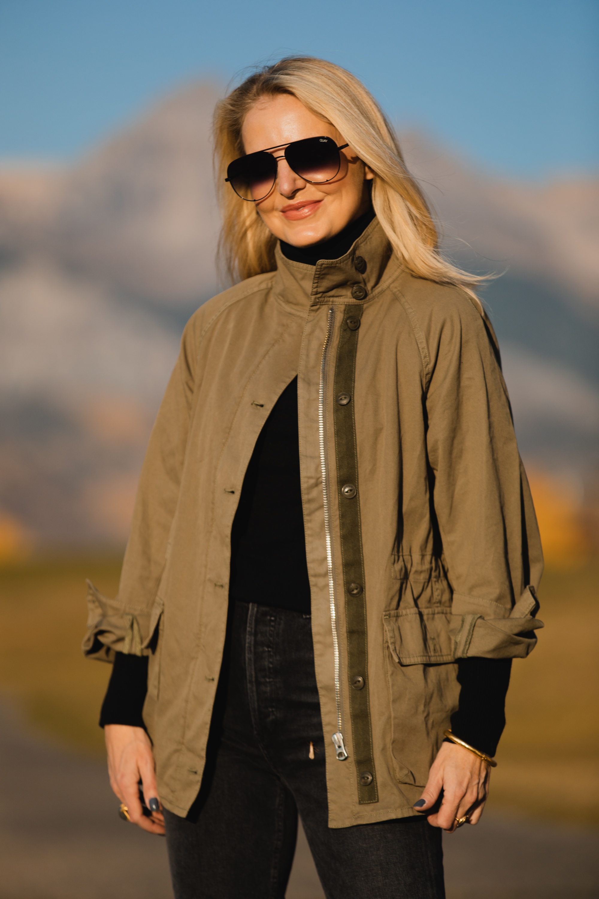 How To Wear A Cargo Jacket, Erin Busbee of Busbee Style wearing a green cargo jacket by rag & bone, black turtleneck puff sleeve cashmere sweater by Aqua, gray wash Nico slim fit jeans by Agolde, QUAY sunglasses, and Alexander Wang cutout booties in Telluride, Colorado