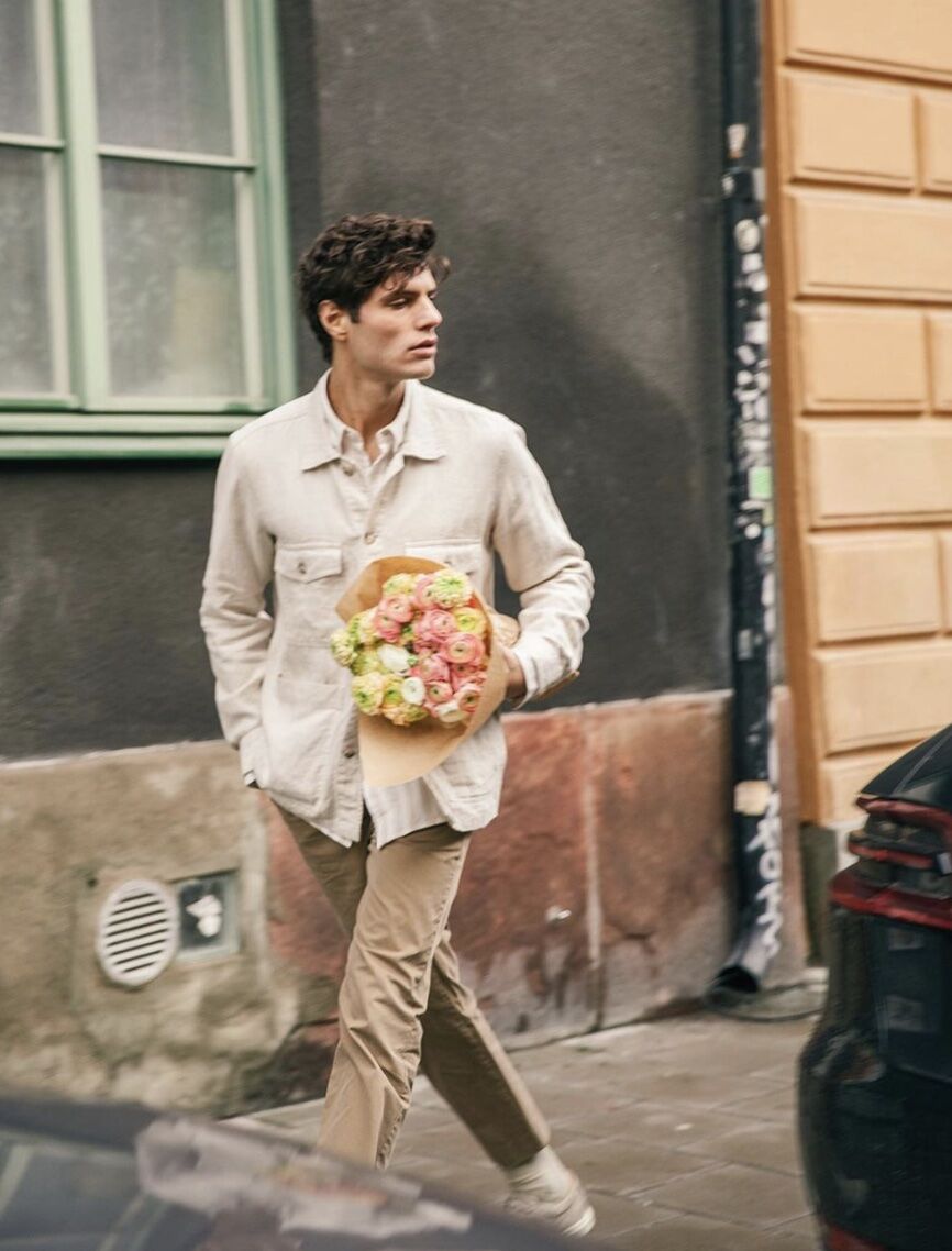 Man walking down the street with flowers, looking away from the camera